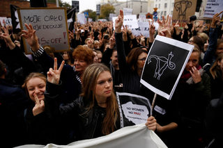 Women gesture as people gather in an abortion rights campaigners' demonstration to protest against plans for a total ban on abortion in front of the ruling party Law and Justice (PiS) headquarters in Warsaw