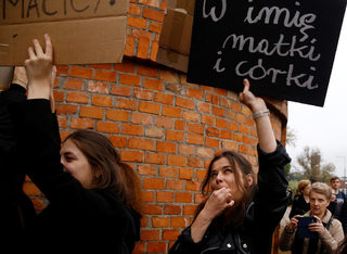 A woman whistles and holds placard as people gather in an abortion rights campaigners' demonstration to protest against plans for a total ban on abortion in front of the ruling party Law and Justice (PiS) headquarters in Warsaw