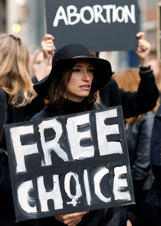 A demonstrator holds a sign to protest against a proposed parliament bill to completely ban abortion in Poland, in front of EU institutions in Brussels