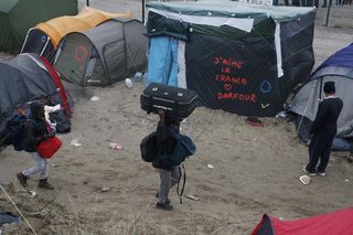 Migrants with their belongings walk past tents at the start of their evacuation and transfer to reception centers in France, and the dismantlement of the camp called the "Jungle" in Calais