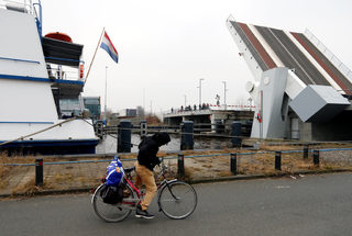 Sall from Guinea rides a bicycle outside a floating hotel in Groningen