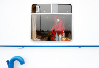 Fartun Maani from Somalia talks on her mobile phone as she poses in a cabin of a floating hotel in Groningen