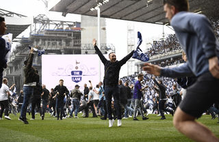 Tottenham fans run on the pitch to celebrate after the match