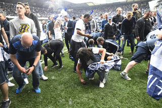 Tottenham fans take part of the pitch grass as they celebrate after the game