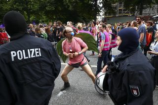 A protester jokes with German riot police officers demonstrations at the G20 summit in Hamburg