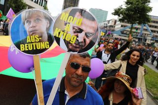 A man holds banners depicting German Chancellor Merkel and Turkish President Erdogan during demonstrations at the G20 summit in Hamburg