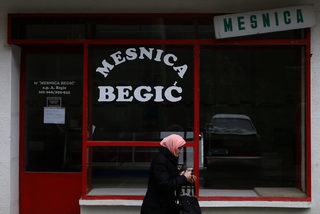 Bosnia Muslim woman passes by closed butcher shop in Srebrenica