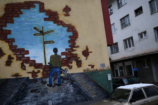Woman passes by mural which say: "peace, happiness, future, success" in Srebrenica