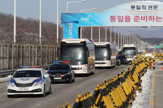 Buses transporting North Korea's women ice hockey athletes drive past a check point of the Grand Unification Bridge near the demilitarized zone separating the two Koreas in Paju