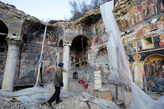 A man is seen walking by the ruins of The Orthodox Church of Saint Athanasios in Leshnica