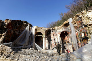 A man is seen walking by the ruins of The Orthodox Church of Saint Athanasios in Leshnica