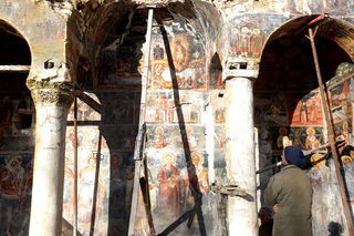 A man looks at a damaged fresco in The Orthodox Church of Saint Athanasios in Leshnica