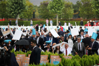 Invitees take cover from the rain as they wait for arrival of Turkish President Erdogan during a ceremony at the Presidential Palace in Ankara