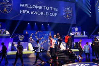 Professional Xbox and Playstation players take their positions for the group stages of the FIFA eWorld Grand Final at the O2 Arena in London