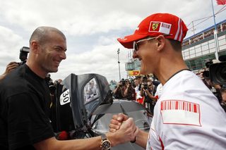 Former Ferrari Formula One driver Schumacher shakes hands with former soccer player Zidane at the Magny Cours circuit