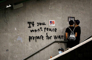 Anti-extradition bill protesters stand next to a graffiti during a march to demand democracy and political reforms in Hong Kong