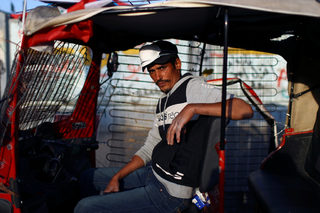 Allawi, a tuk-tuk driver, poses for a photograph during the ongoing anti-government protests in Baghdad