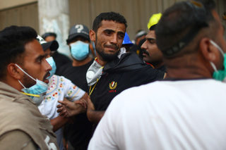 An Iraqi demonstrator reacts after his friends was killed during the ongoing anti-government protests in Baghdad