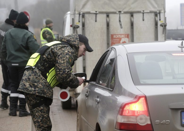 Литавски граничар проверява автомобили на границата при Зарасаи на 8 март.