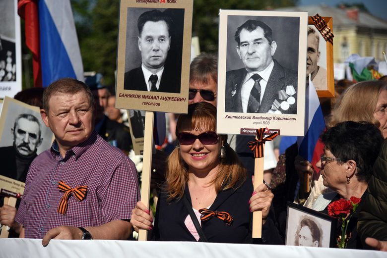 Участници в шествието носят плакати с портрети на загинали във войната свои роднини или партизани.
