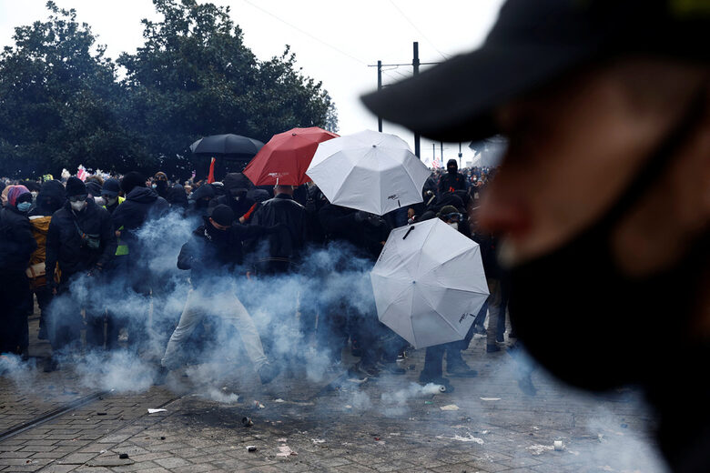  Протестиращи се прикриват с чадъри и с маски от сълзотворния газ, употребен против тях от полицията в Нант 