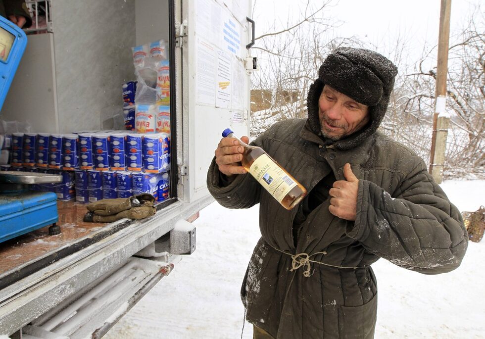 Мъж купува бутилка вино от мобилния магазин в почти изоставеното село Рудное.