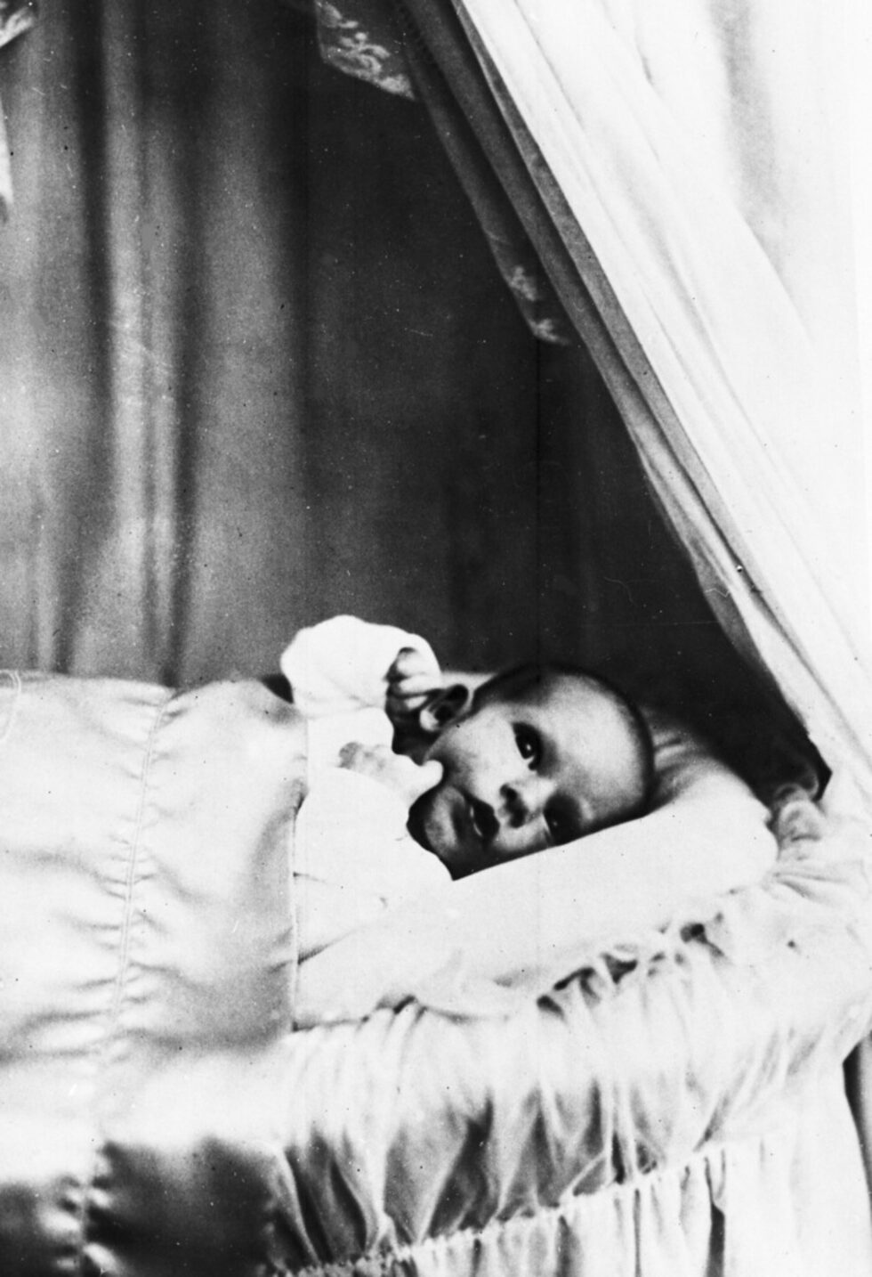 Симеон Сакскобургготски е цар на българите в периода 1943 - 1946 година и министър-председател на България в периода 2001 - 2005 година. Днес навършва 75 години.<br /><br />Симеон е роден с титлата <em>княз Симеон Търновски</em>, син на цар Борис III и на царица Йоанна Савойска и престолонаследник на българския трон. От смъртта на цар Борис III на 28 август 1943 до 15 септември 1946 г. е цар на България, но поради ранната си възраст не встъпва в длъжност и от негово име управлява Регентски съвет.През 1946 г., след референдум Цар Симеон II, сестра му Княгиня Мария Луиза и Царица Иоанна са принудени да напуснат България. <br /><br /> На снимката: Снимака на Симеон след кръщенето му  на 12 юли 1937 г., София.