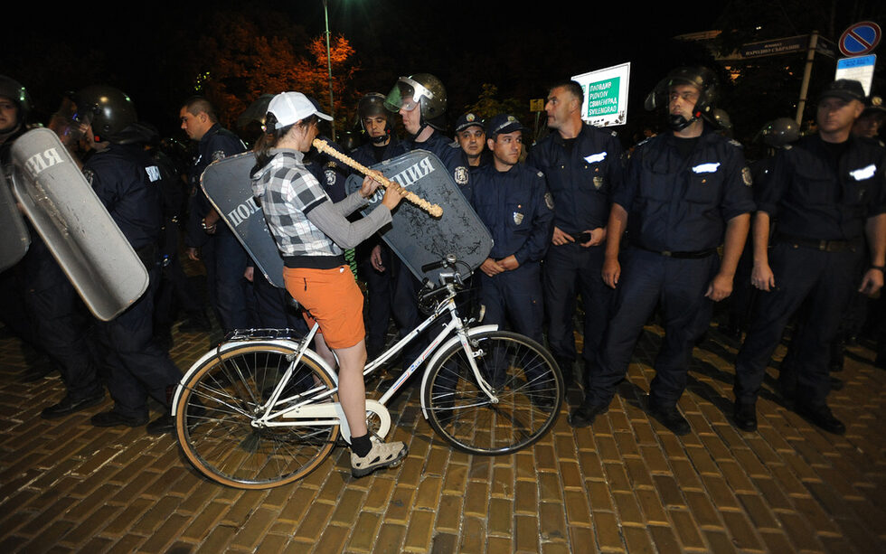 Полицаите са развалили вече блокадата на жълтите павета и 3 часа след полунош, кордон прави все по-широк коридор, като настъпва към паметника, за да отблъсне протестиращи. <br />
<br />
Те се опитват да задържат позициите си. Това момиче застава с инструмента си за свирене (тя е от редовните участници в шествията). Малко след това полицаите тръгват и я събарят с колелото. <br />
<br />
Те разширяват още повече коридора към СУ. Започва да се обсъжда, че може би точно от тук ще изведат отново автобуса или депутатите по друг начин. Кордон застава и на кръстовището пред университета, където също има барикада и протестиращи. <br />
