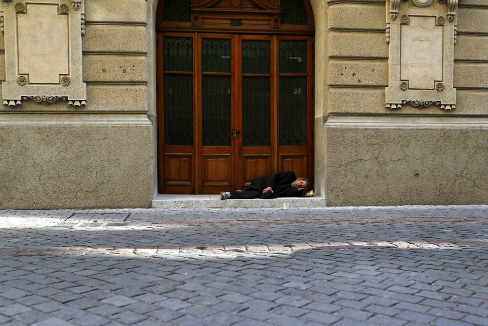 Мъж спи на прага на фондовата борса в Сантияго, Чили.