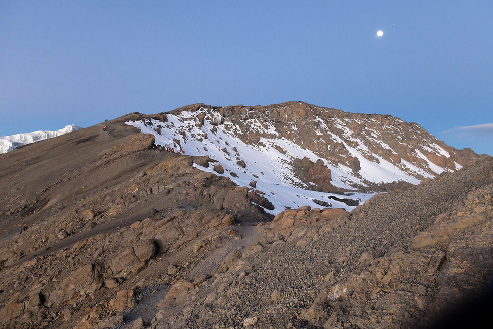 Отпред е Stella Point, пресечна точка на ръба на планината. Тук билото бива достигнато от още един маршрут. По склона идват още катерачи. Връх Ухуру е напред.