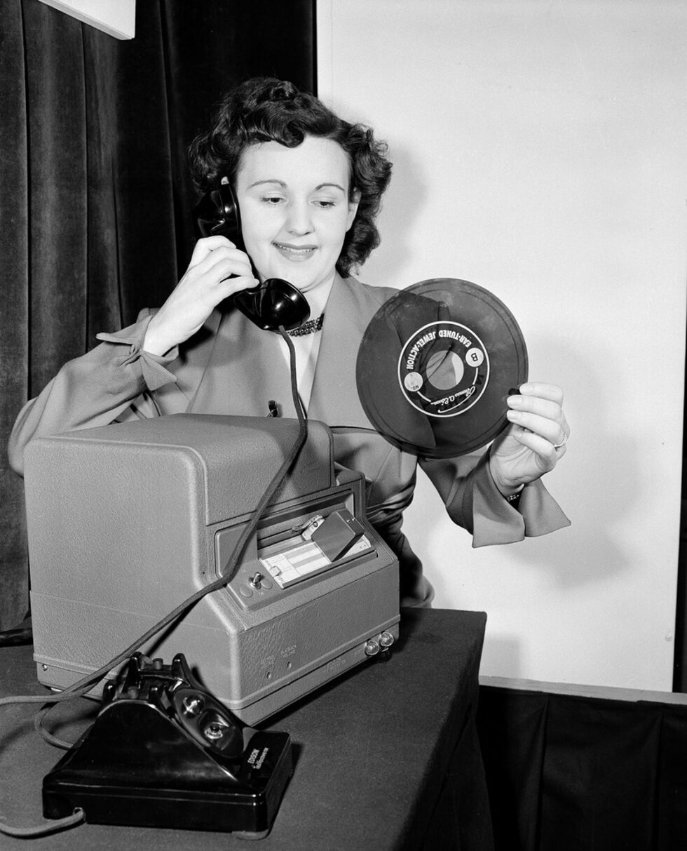Джпам Куеснел държи диск, който се използва от новия Edison TeleVoicewriter, който е представен на 26 февруари 1951 г. Това е първият своеобразен телефонен секретар. Той записва съобщения, които след това служителите на компанията са прехвърляли на хартия.