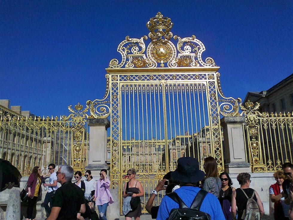 Пред портите на Версай. Кралят-слънце си е почивал тук от парижките интриги, замисляйки нови от разстояние, и зареждайки се с ценни мисли при дългите разходки в градината.