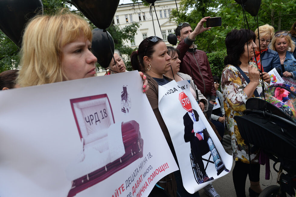 Протестите започнаха през 2015 г. с искане на родителите на деца с увреждания за по-адекватни грижи и услуги за децата им. Миналата година точно преди поредния протест правителството (вторият кабинет "Борисов") <a href="http://www.dnevnik.bg/bulgaria/2016/09/13/2826503_pravitelstvoto_planira_uvelichenie_na_mesechnata/" target="_blank">спешно прие увеличение на помощите за децата с най-висока степен на увреждане (над 90%)</a> и с по-малко за останалите категории. <br /><br />Това обаче се оказва лоша услуга, защото на практика помощите за едните се увеличиха за сметка на другите, а родителите, които вече получават по-голяма месечна помощ, губят възможността да се водят на работа към общината като личен асистент на детето си, разказаха за "Дневник" организаторите на протеста.