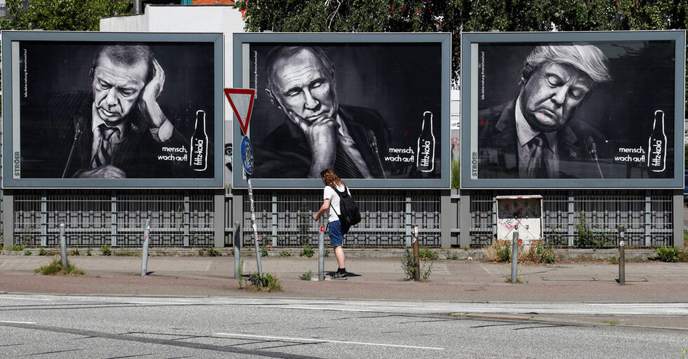 Мъж минава покрай рекламен постер с портрети на Ердоган, Путин и Тръмп ден преди началото на срещата на Г20 в Хамбург, Германия.