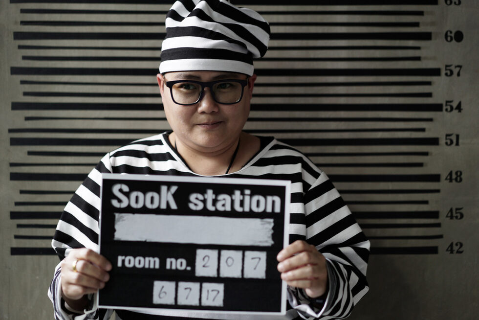 Хостелът Sook Station в квартал "Удом Сук" в Банкок предлага на гостите си класически затворнически пижами с райета и стена с мярка за височина, пред която могат да се снимат.