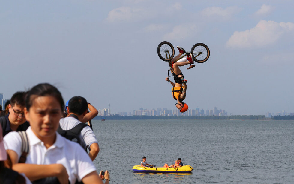 Човек скача с BMX в езеро в Ухан, провинция Хубей, Китай.