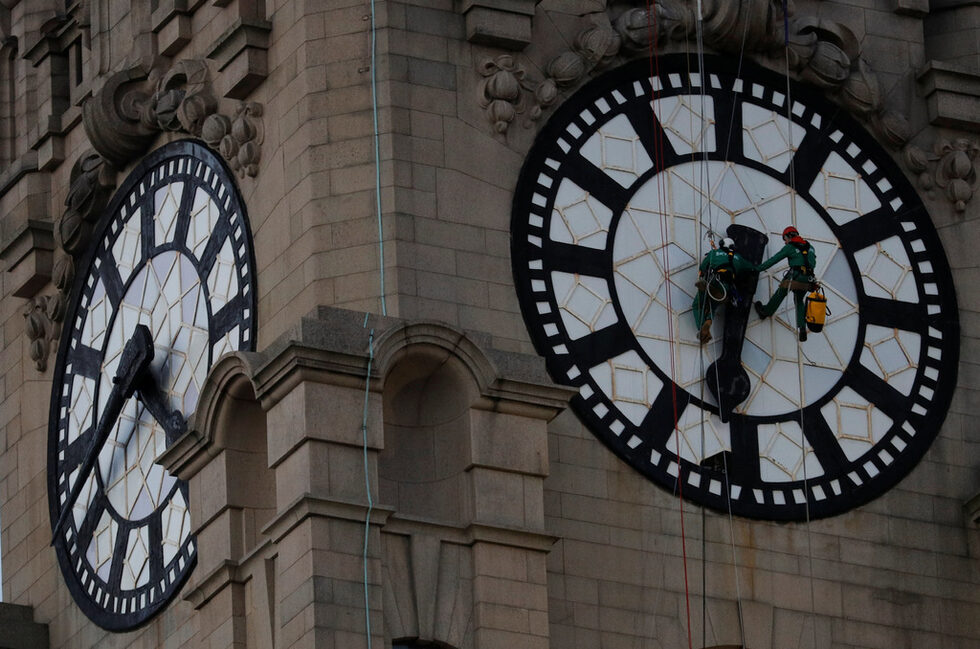 Работници почистват часовника на Royal Liver Buildings в Ливърпул, Великобритания.