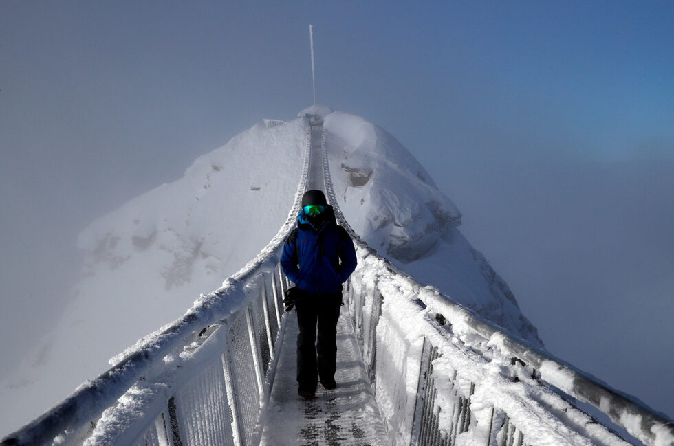 Сноубордист се разхожда по моста Peak Walk в Швейцария.