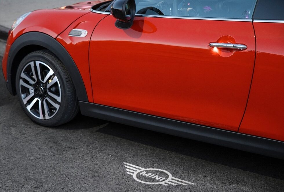 Част от опционалния пакет MINI Excitement е и проекцията на логото на марката от страната на водача. При отключване и заключване на автомобила новото лого се проектира от светлинен източник във външното огледало върху областта пред вратата и се вижда там за 20 секунди, както и постоянно при отворена врата.