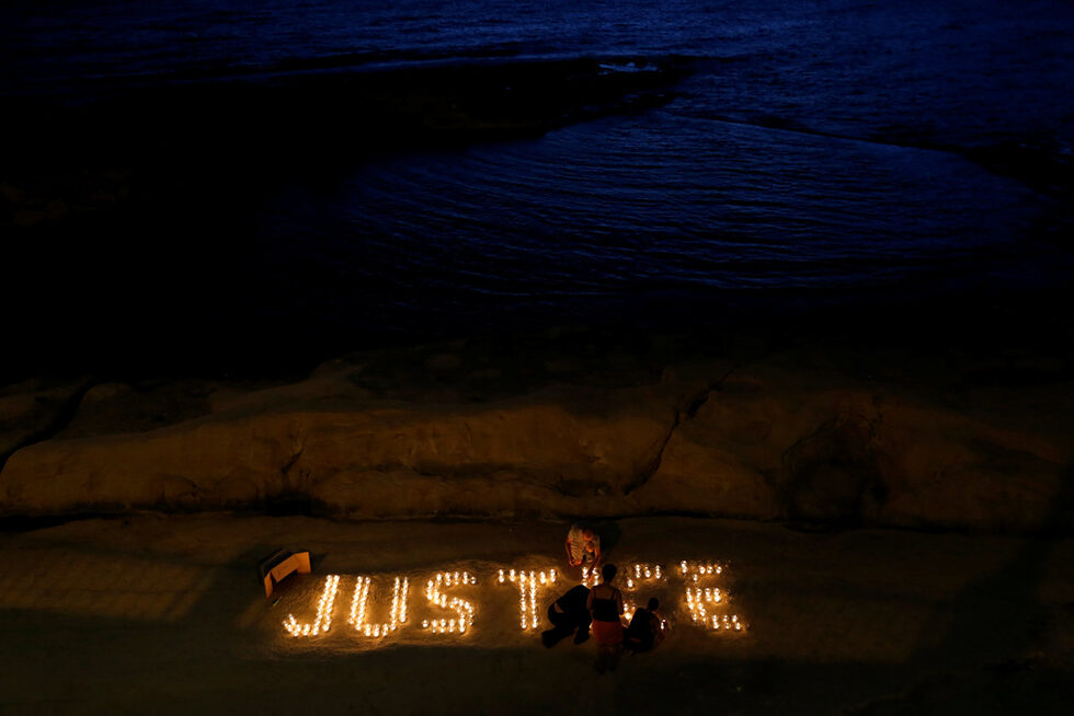 Активисти от антикорупционната група Occupy Justice палят свещи на плажа в Слима, Малта, за да отбележат десет месеца от убийството на разследващия журналист Дафне Каруана Галиция.