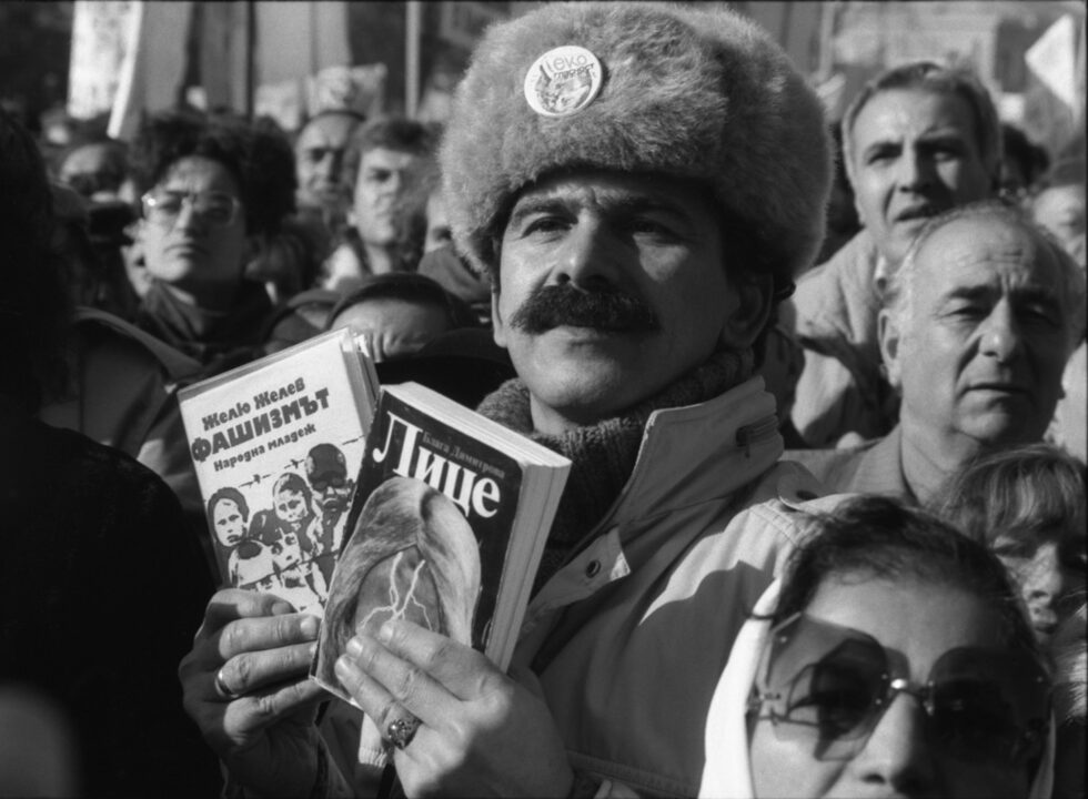 Първият свободен митинг след падането от власт на диктатора Тодор Живков събира хиляди хора на 18 ноември 1989 г. на площад "Св. Александър Невски" в София. Участник носи книгите "Фашизмът" на Желю Желев и "Лице" на Блага Димитрова - и двете забранени при комунизма. Кадрите са предоставени на "Дневник" от Николай Василев