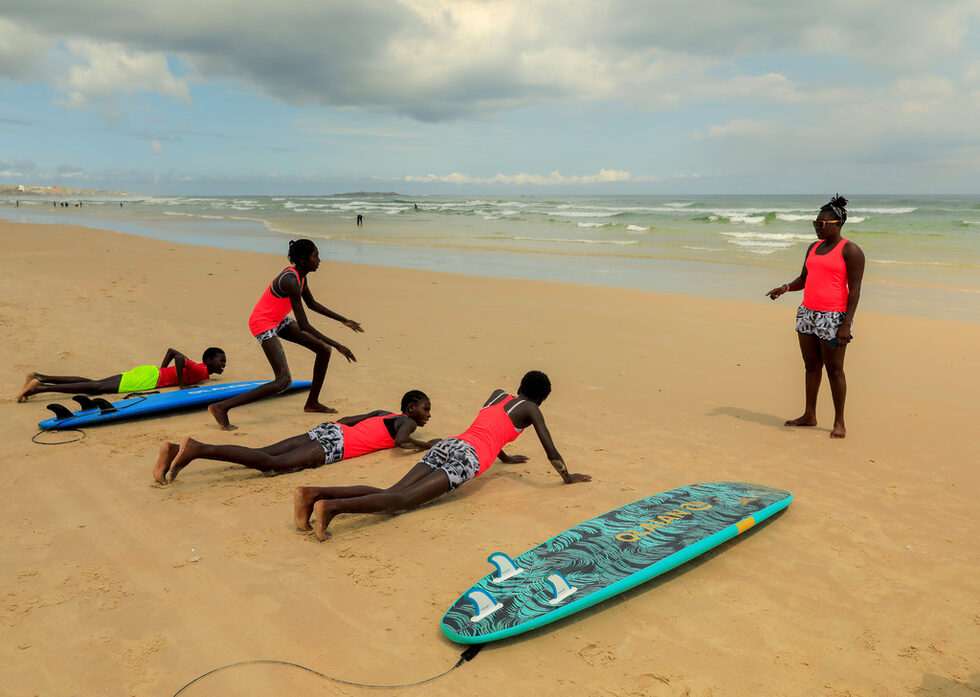 Самбе е част от проекта Black Girls Surf, който помага на тъмнокожите момичета и жени по света да извървят стъпките към професионалния спорт.<br /><br />Тя тренира местни момичета и ги учи да развиват силата на тялото и ума. Самбе се опитва да изкорени стереотипните схващания в културата й, че жените трябва да се омъжат млади и да стоят предимно вкъщи, за да готвят и чистят.<br /><br />"Винаги ги съветвам да не слушат другите и да си запушват ушите", разказва Самбе пред "Ройтерс".