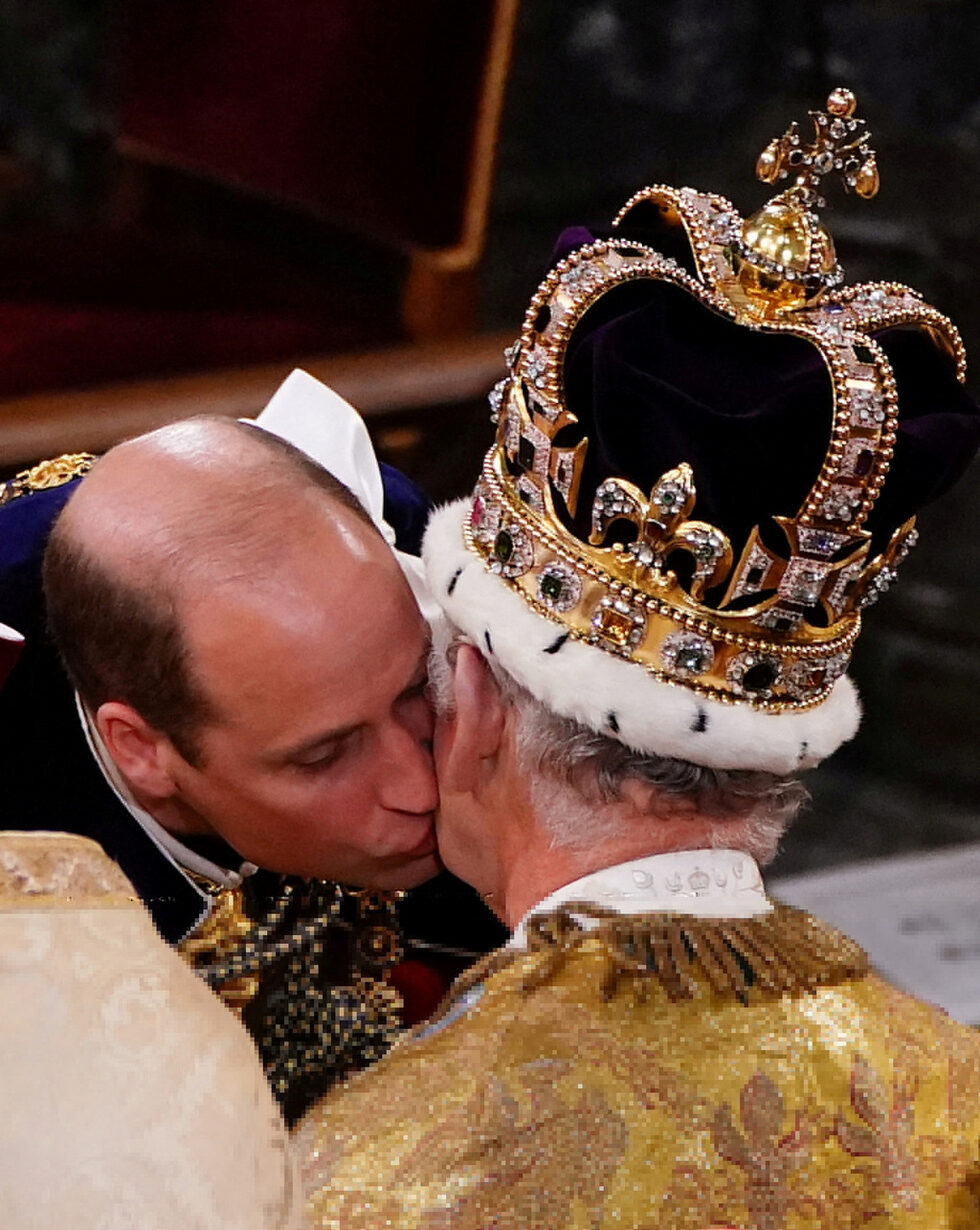 Британският принц на Уелс Уилям целува баща си крал Чарлз III по време на церемонията по коронацията му.
