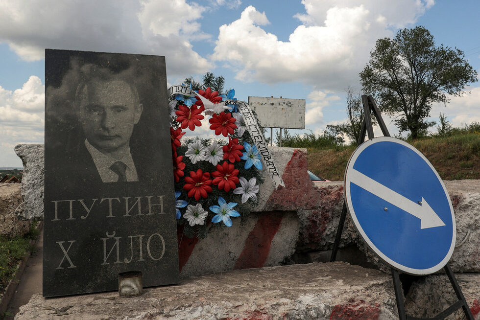 Погребален венец, надгробна плоча с нецензурен надпис и портрет на руския президент Владимир Путин край път в Донецка област, Украйна.
