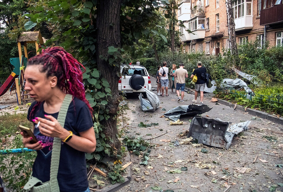 Хора стоят до повредена жилищна сграда, след руски ракетен удар в Киев, Украйна.