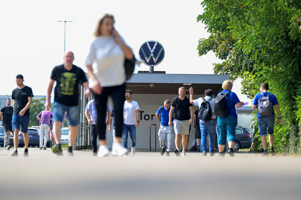 Служители на Volkswagen на фона на портала на завода във Волфсбург преди редовната среща на работния съвет на предприятието с работниците в Германия, на която ще се обсъждат въпроси около напредъка в програмата за намаляване на разходите на компанията, Волфсбург, Германия.