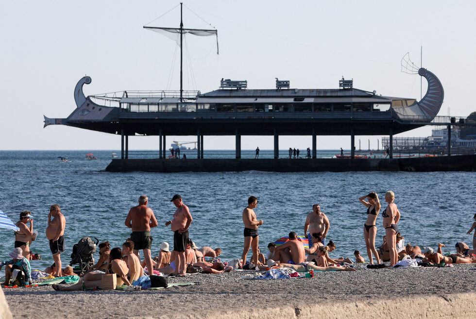Плажуващи разпускат на плажа в черноморския курорт Ялта, Крим.